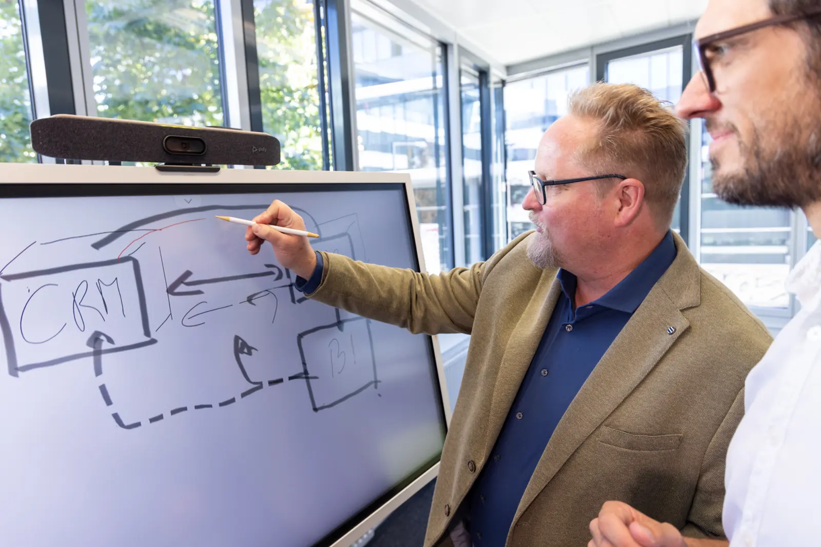 Berater skizziert Systeme und ihre Verbindungen auf einem digitalen Whiteboard, ein Kollege sieht zu