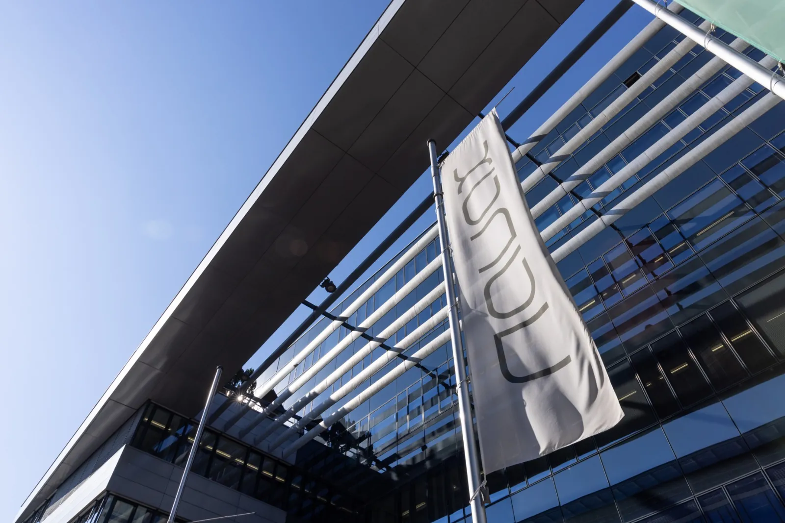Flag with the NAVAX logo in front of a glass facade