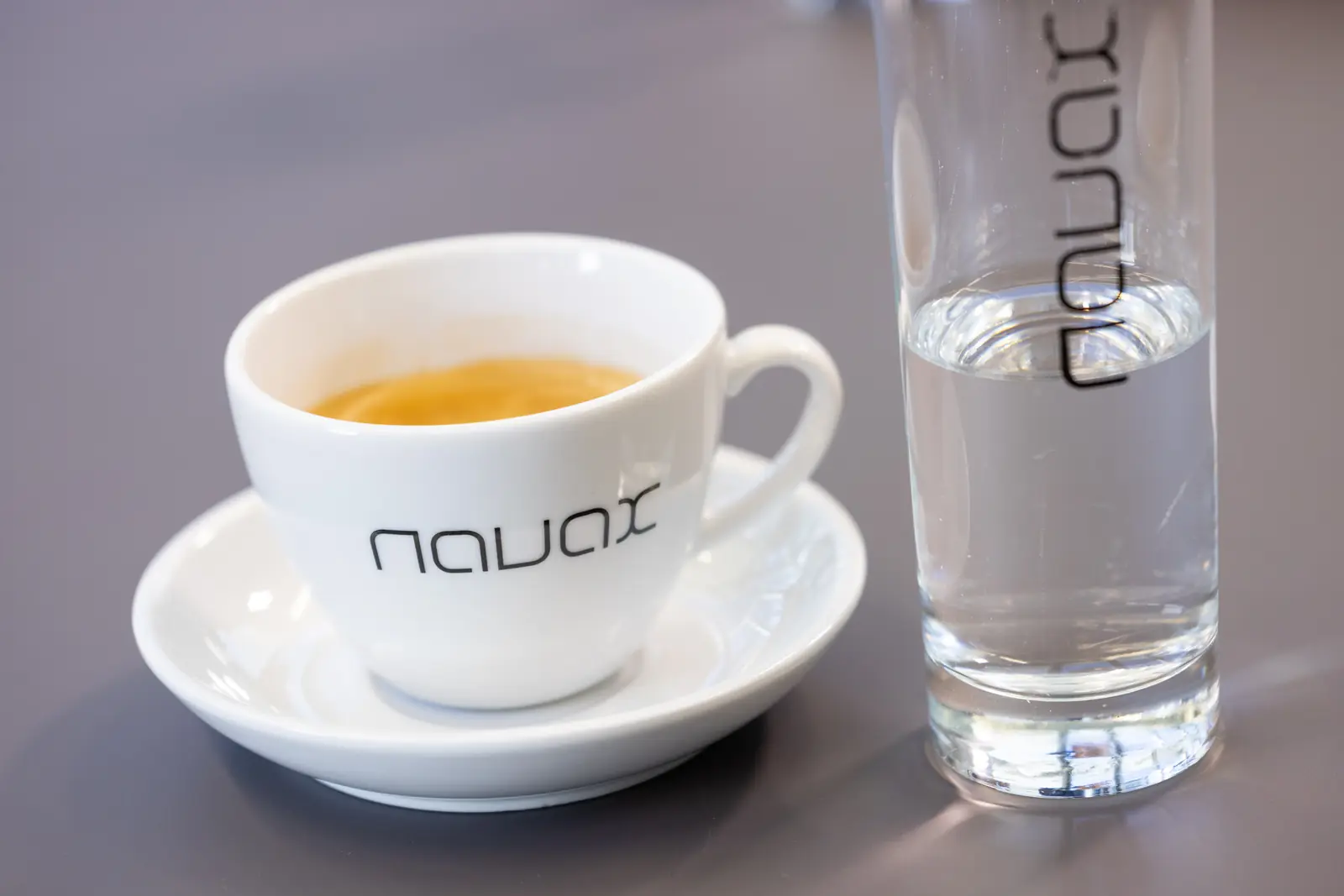 Mug with the NAVAX logo and a glass of water on a meeting table