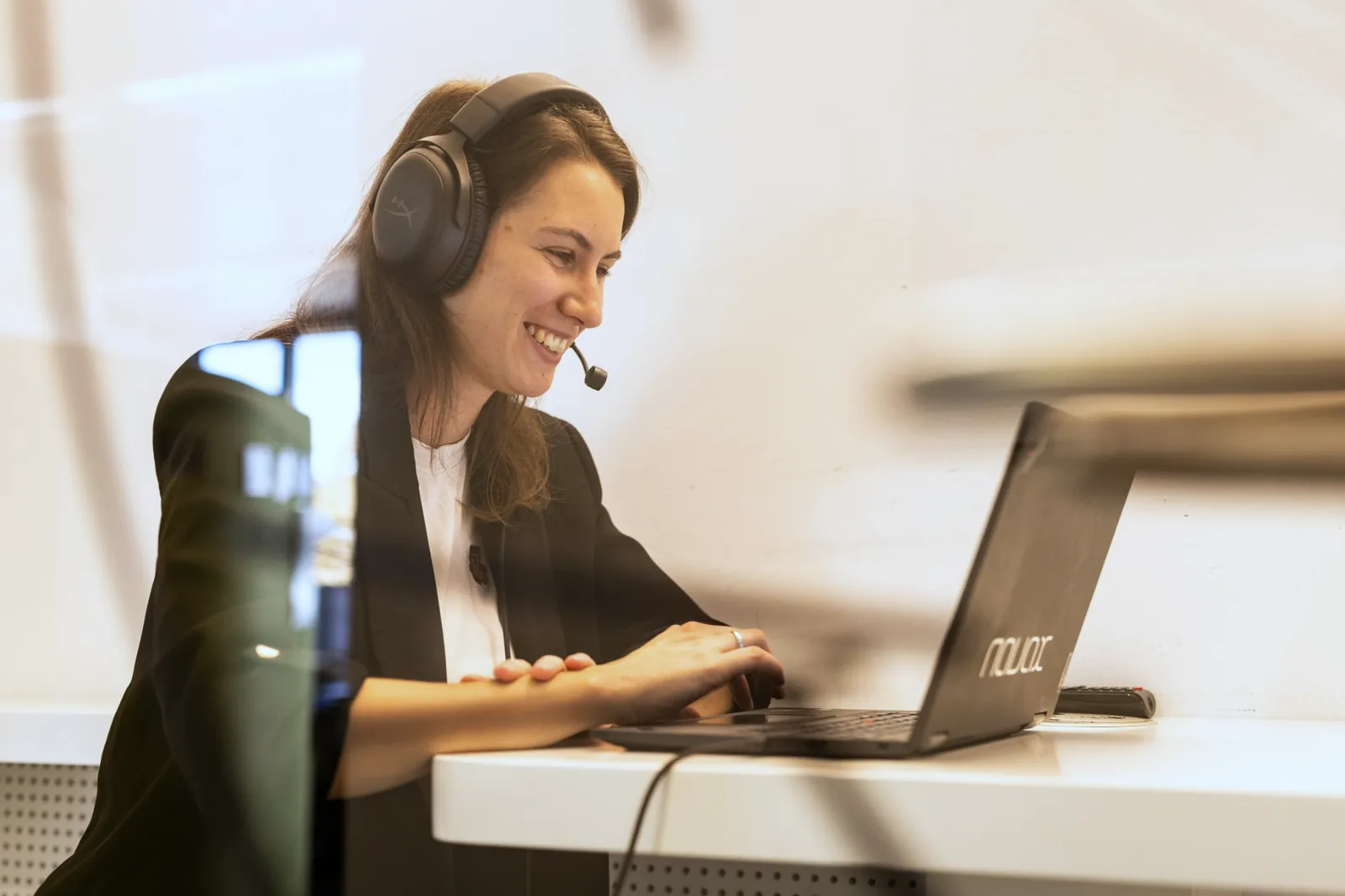 Eine Kollegin mit Headset arbeitet am Laptop