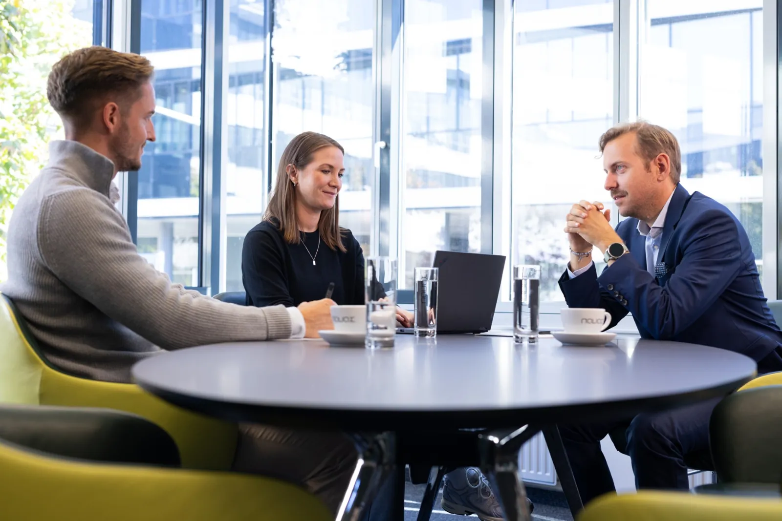 Drei Personen im Gespräch an einem Besprechungstisch