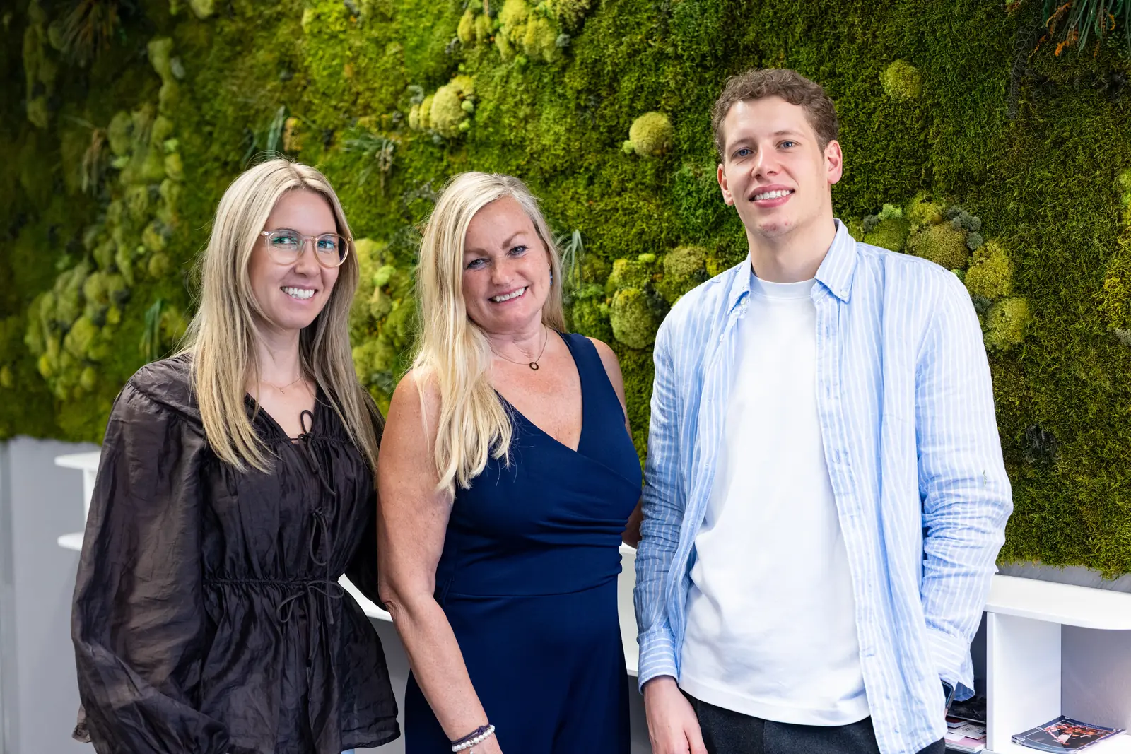 Three colleagues in front of a moss wall