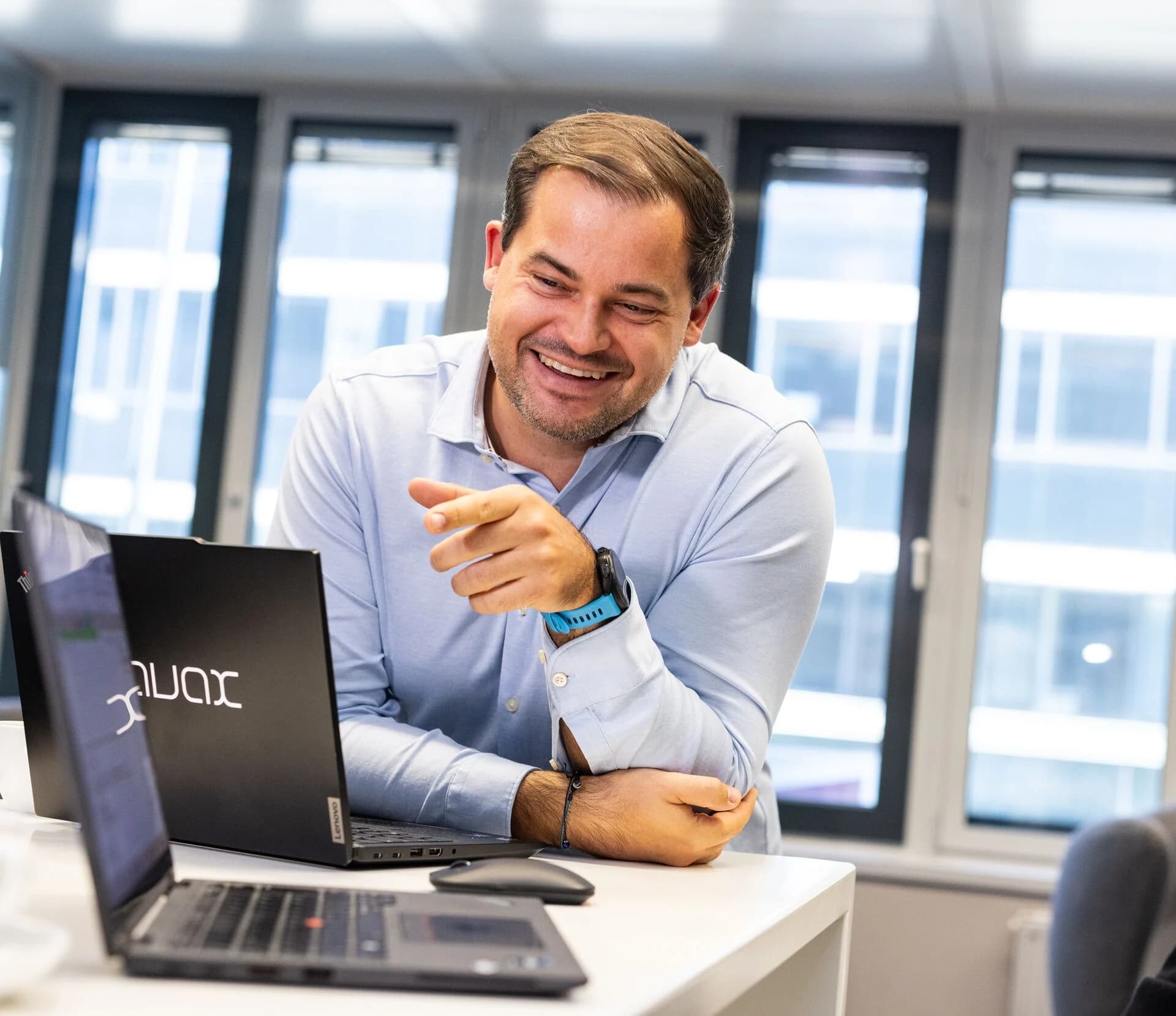 Ein Mann zeigt lachend auf den Bildschirm seines Laptops