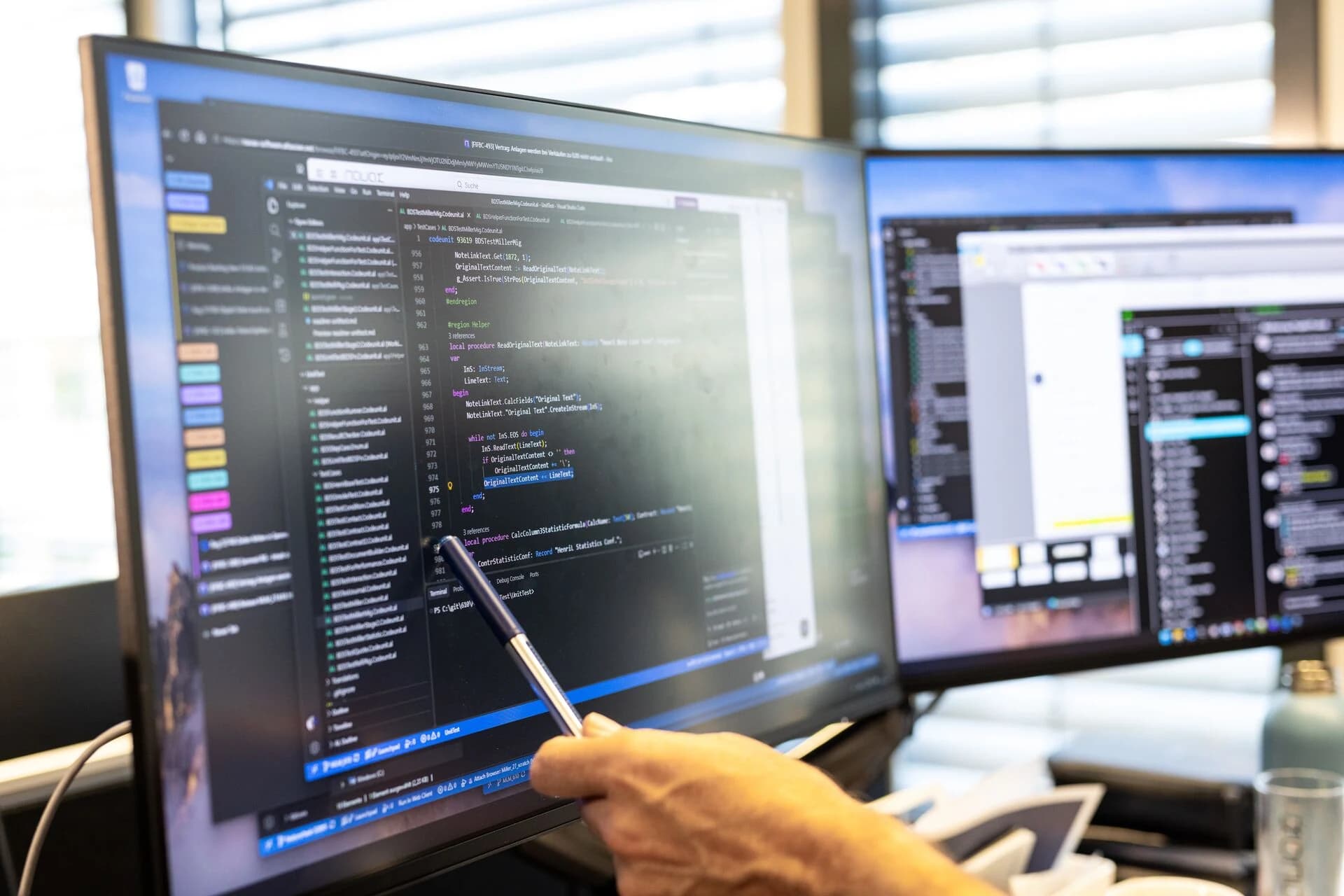 Ein Stift zeigt auf Programmcode am Bildschirm