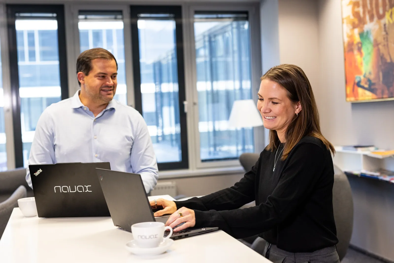 Two colleagues working on laptops at a shared table