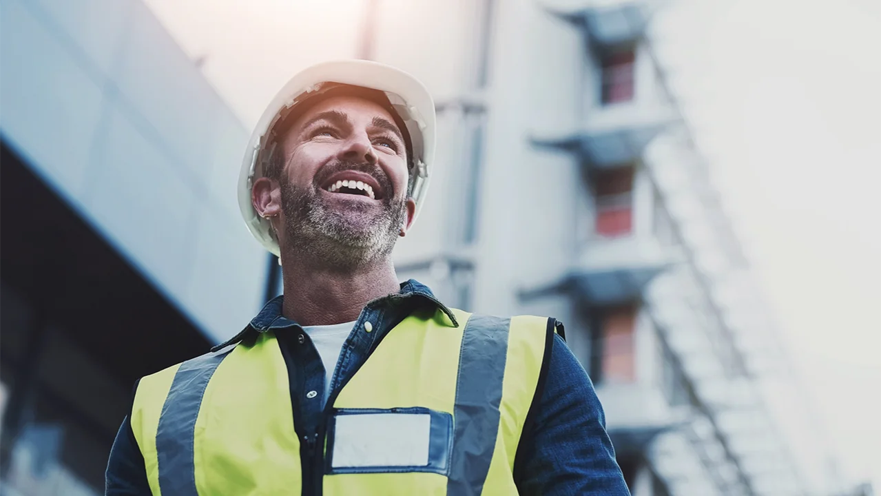 Mann arbeitet auf der Baustelle und lÀchelt