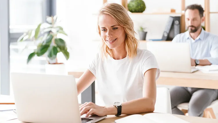 Mitarbeiterin im Professional Services freut sich vor dem Laptop