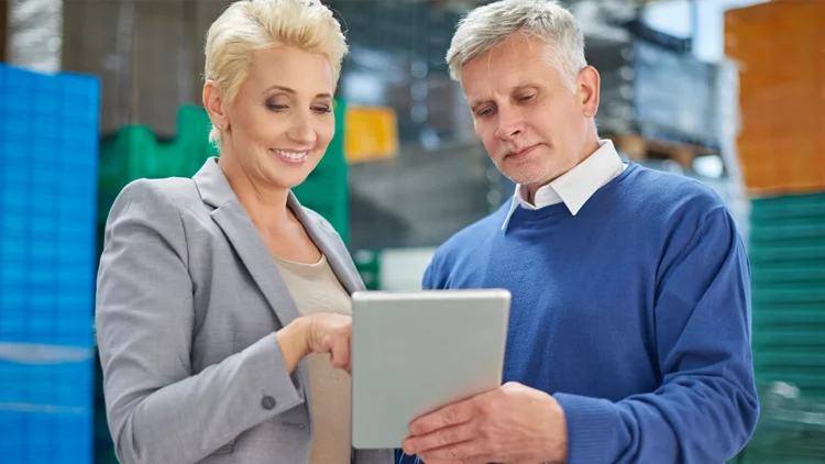 Employees in a production plant check the reporting on an Ipad